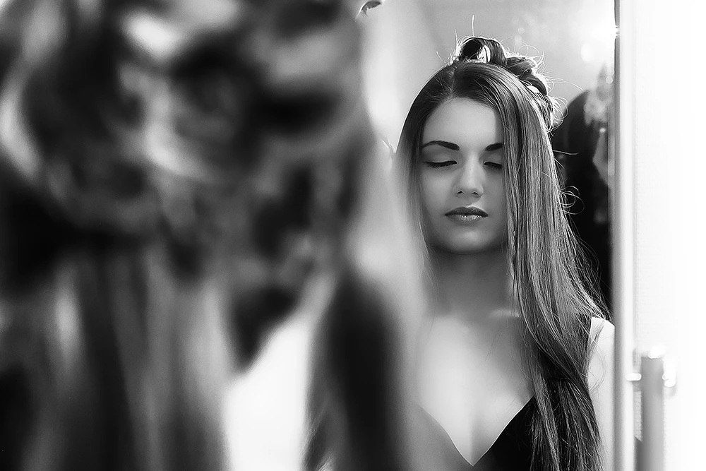 Photo en noir et blanc d'une jeune femme qui se fait coiffer